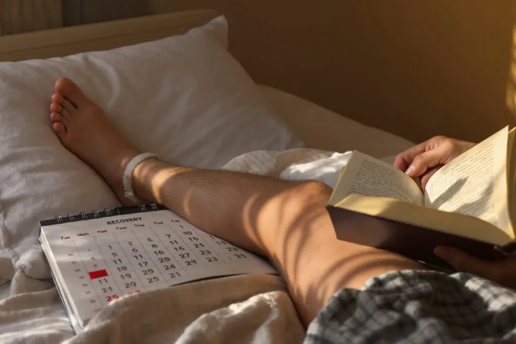 ein bein das sich auf einem kissen erholt neben einem kalender als antwort darauf wie lange man nach einer meniskus-op krankgeschrieben ist