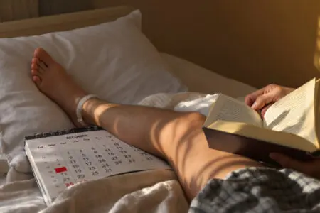 ein bein das sich auf einem kissen erholt neben einem kalender als antwort darauf wie lange man nach einer meniskus-op krankgeschrieben ist